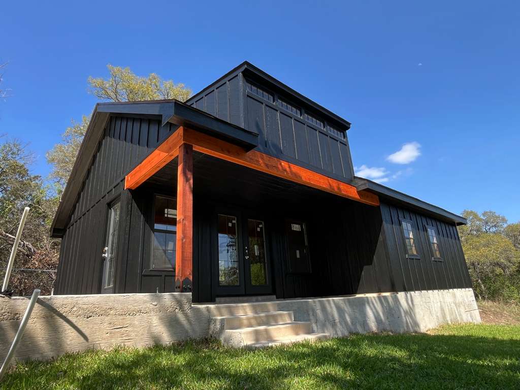 A black custom The Shedfather shed with a front porch and finished exterior